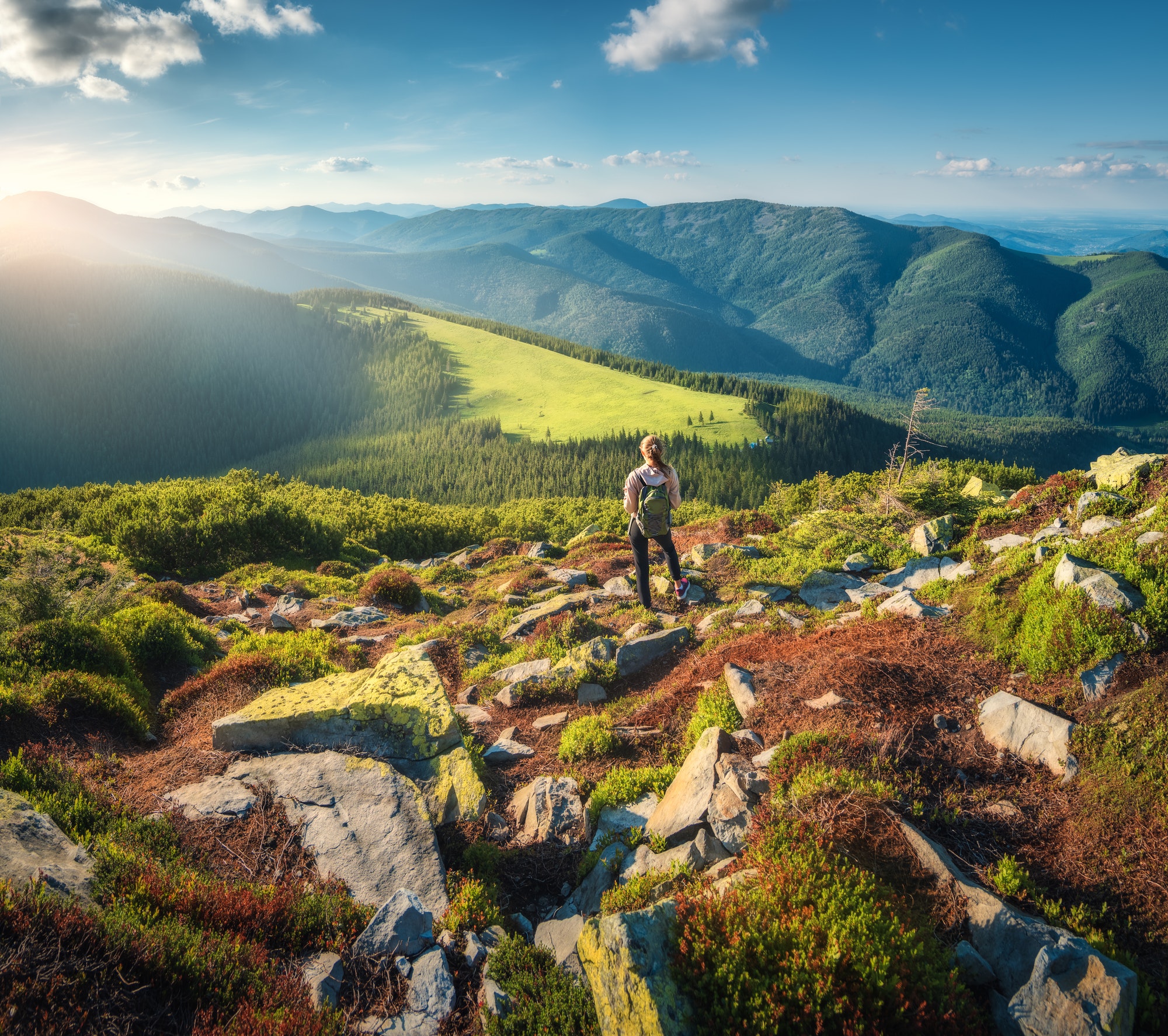 mountains-and-standing-young-woman-with-backpack-on-the-stones.jpg